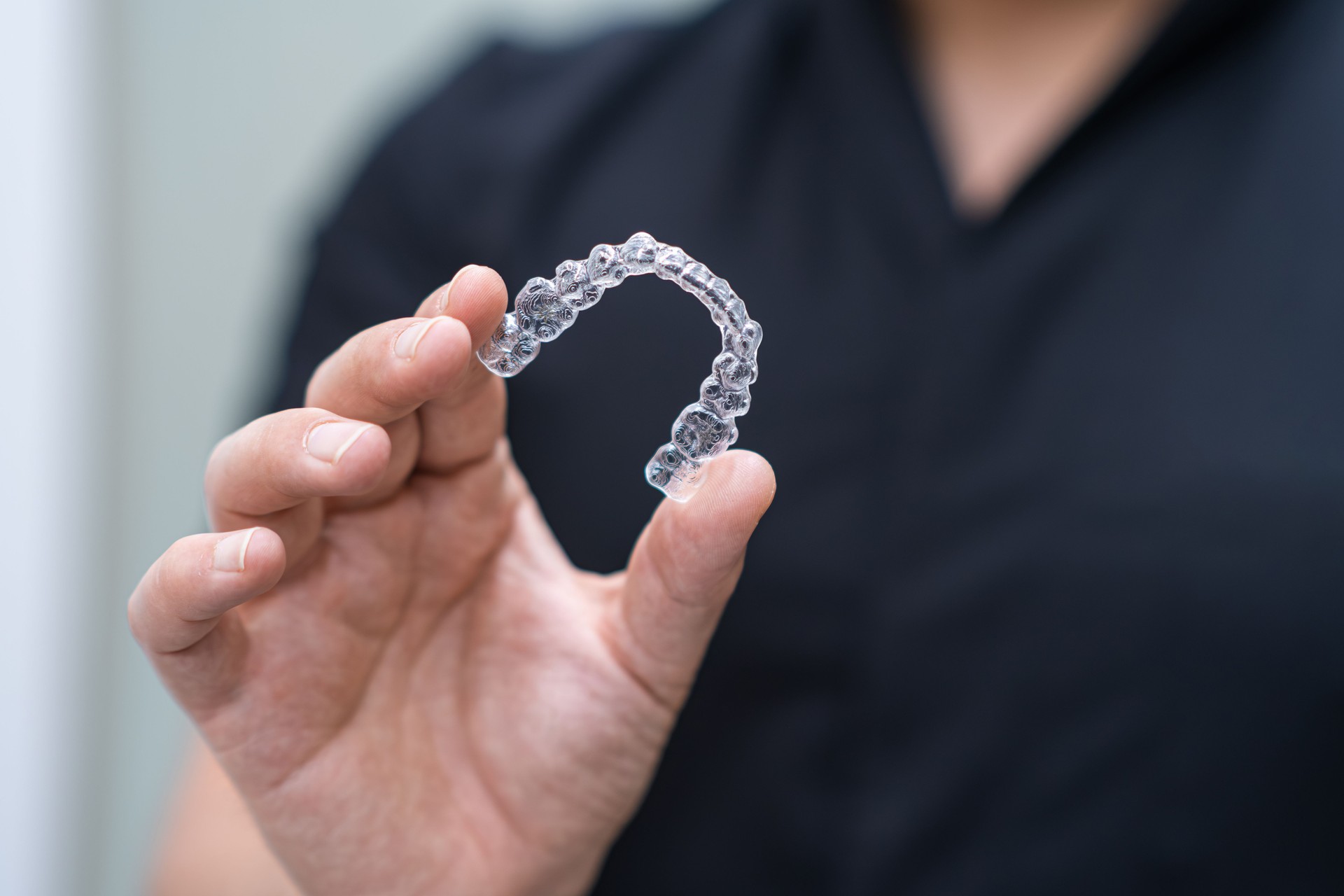 Dentista en uniforme negro sosteniendo alineadores transparentes de herramienta de tratamiento de ortodoncia para el cuidado de los dientes